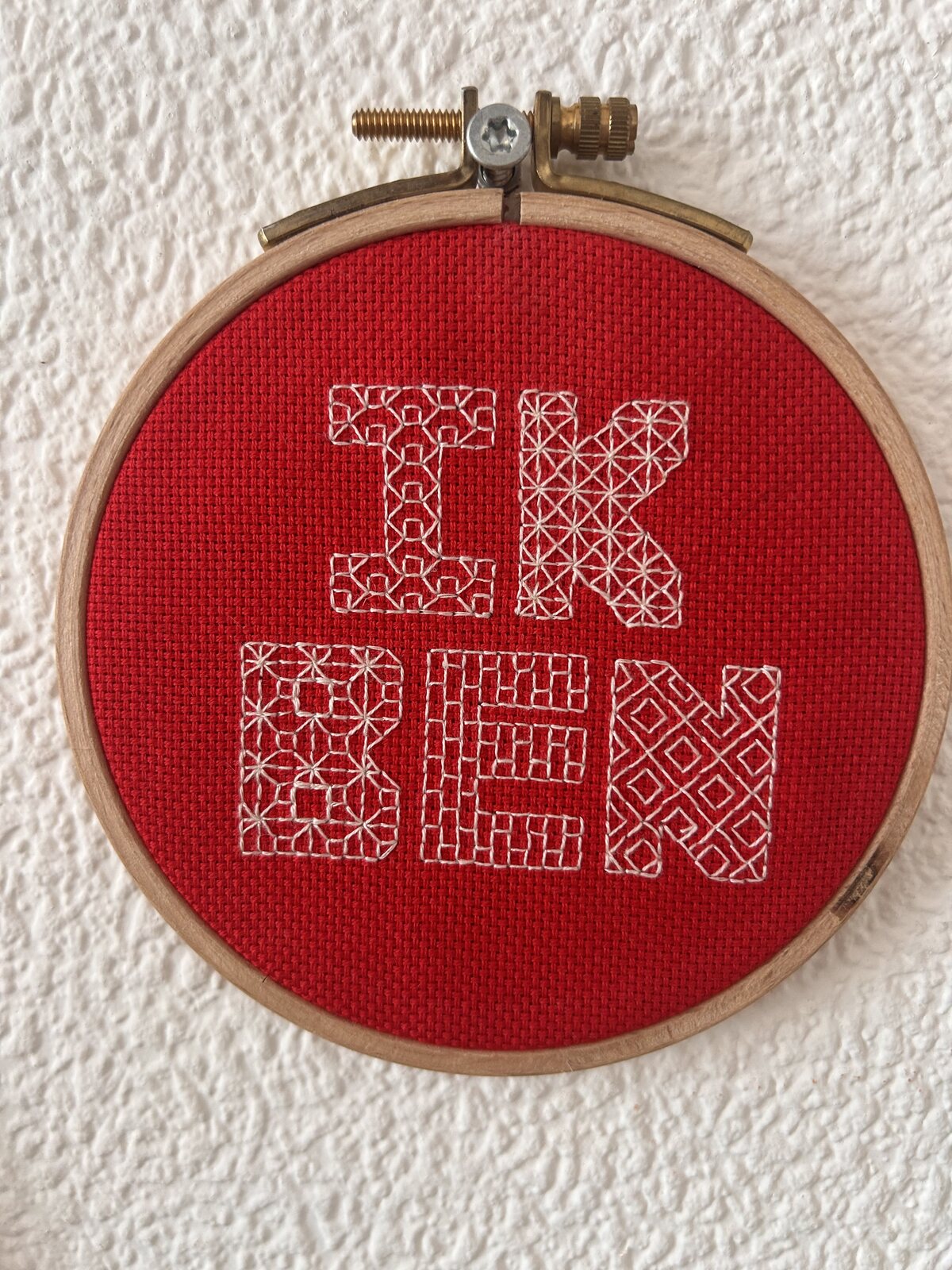 Rood borduurwerk met de tekst Ik ben in een ronde borduurring